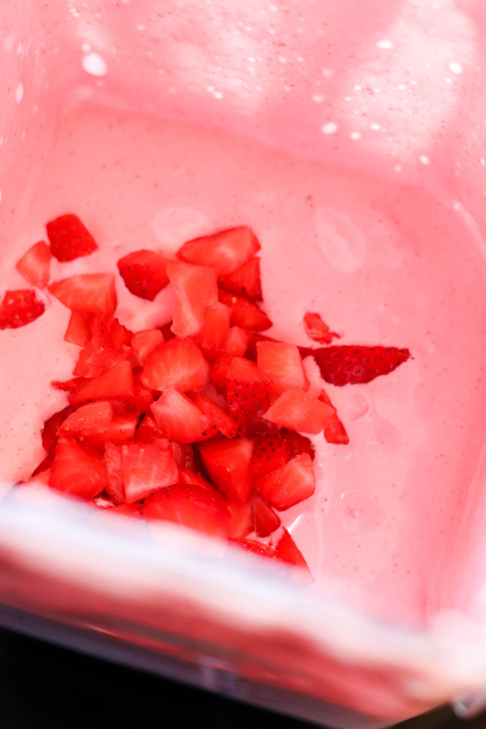 Fresh strawberries on top of strawberry puree in blender