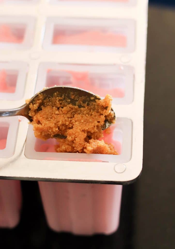 Spooning cheesecake topping onto popsicle mold.