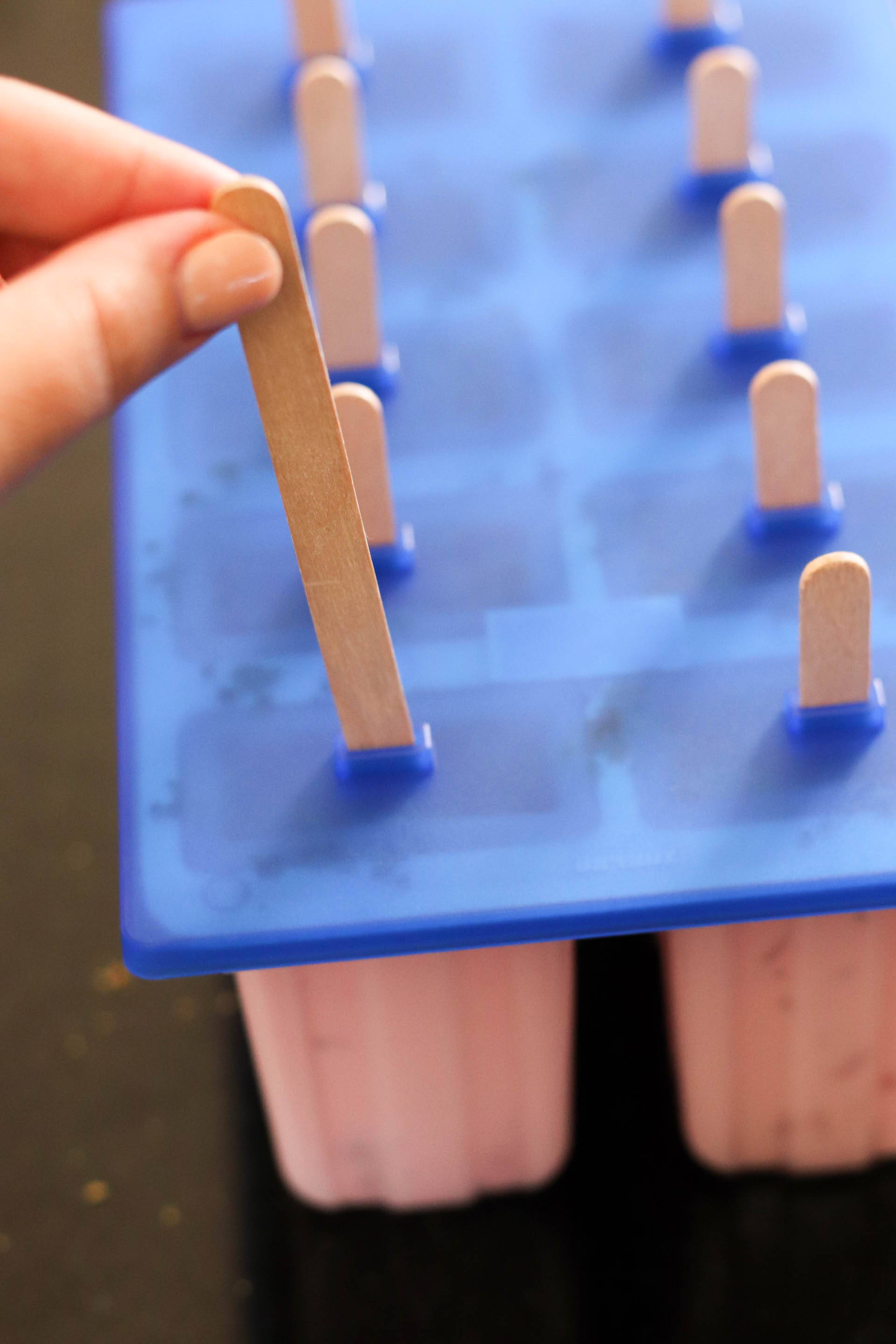 Placing popsicle sticks into the popsicle mold
