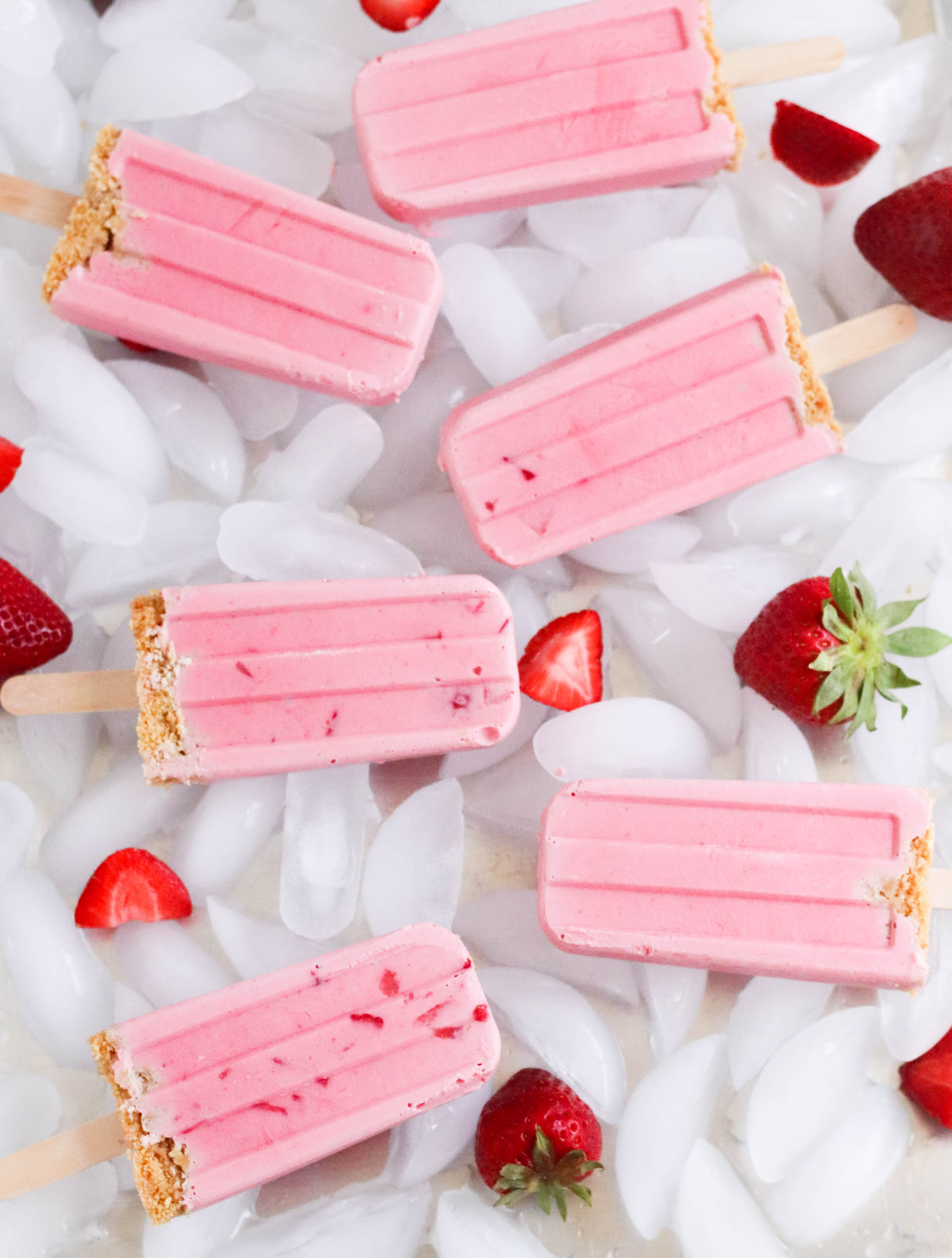 Strawberry Cheesecake Popsicles on ice with fresh strawberries