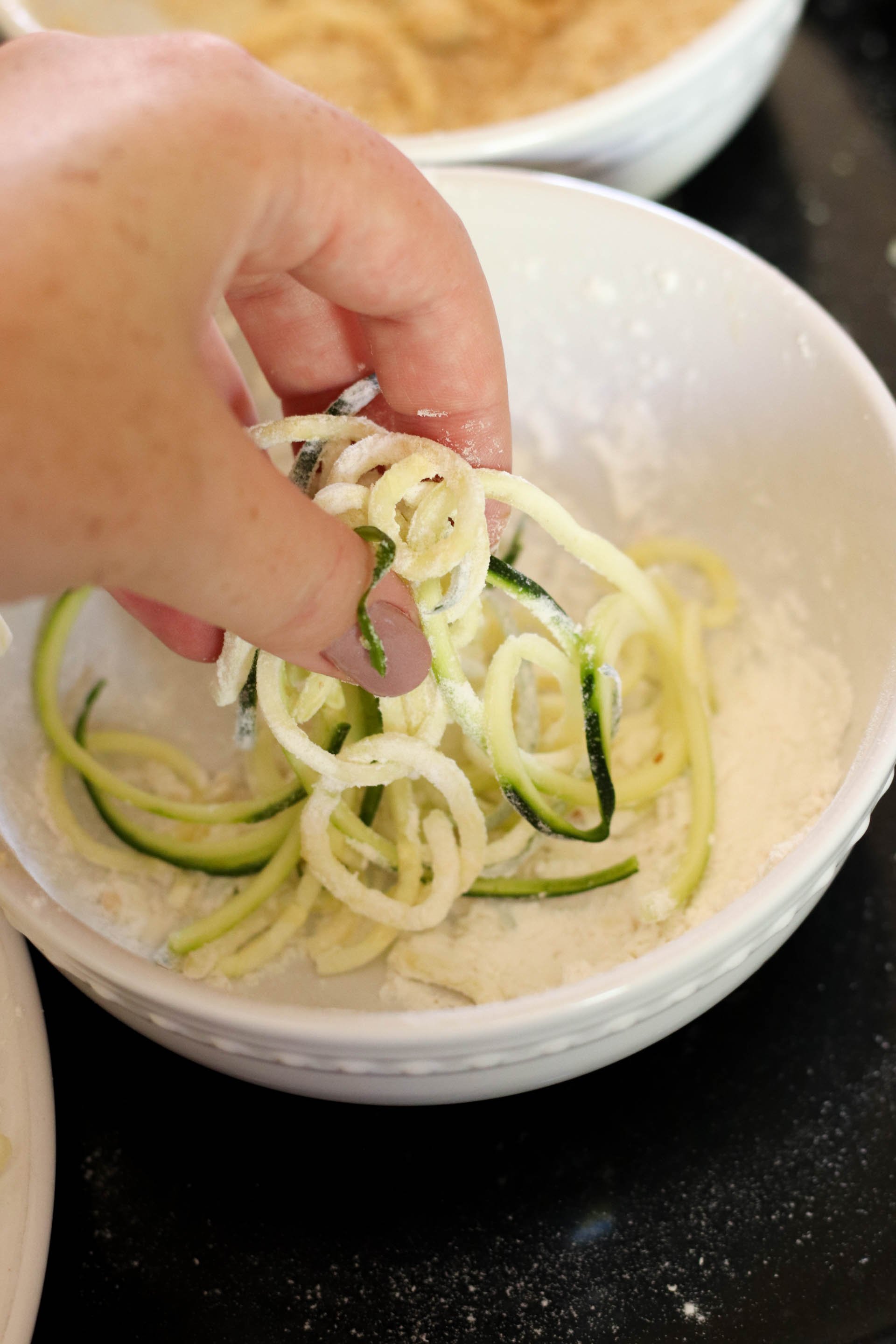 Dipping zucchini strings in flour