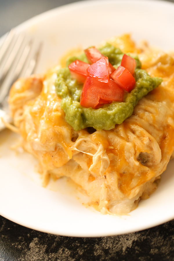 A slice of Chicken Enchilada Casserole on a plate with toppings