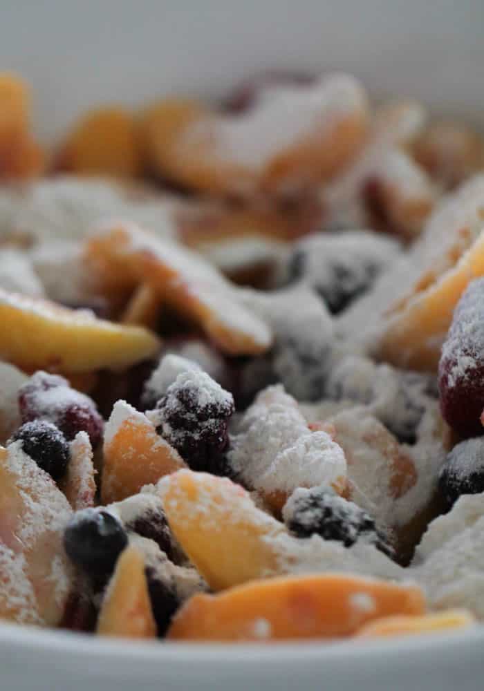 Flour and Sugar mixture tossed with frozen fruit in mixing bowl.