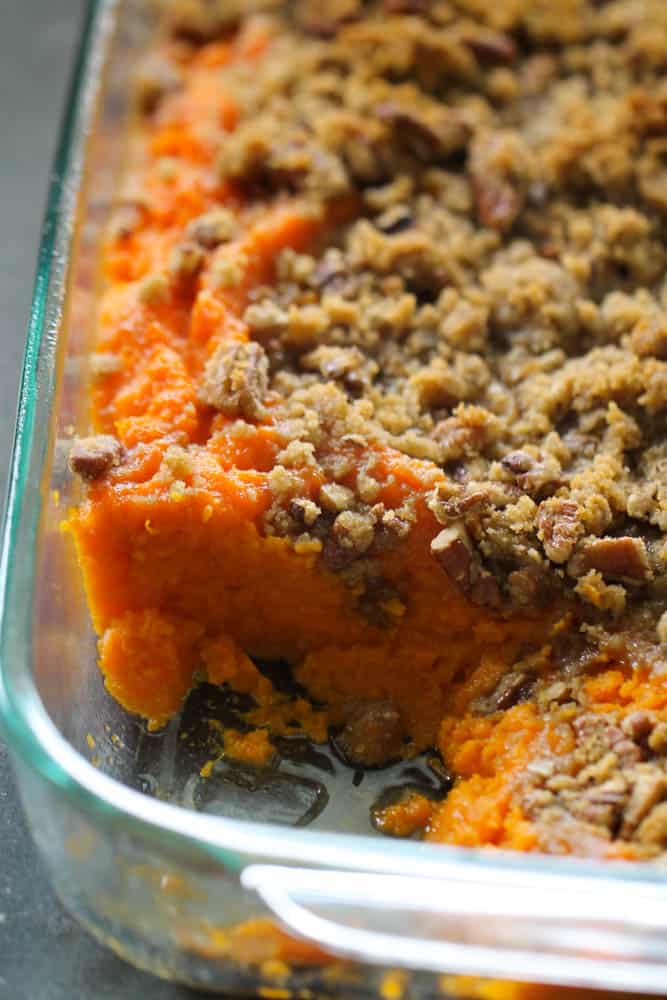 sweet potato casserole with brown sugar and pecan topping with a piece taken out