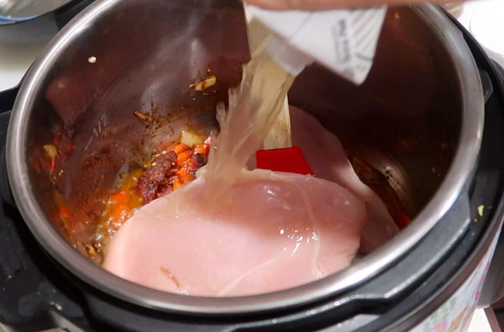 Chicken, onions and pepper in Instant Pot with broth poured on top