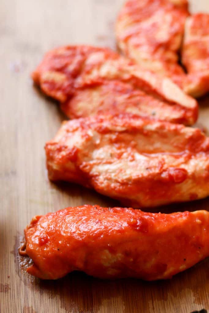 Cooked chicken with pasta sauce on them.