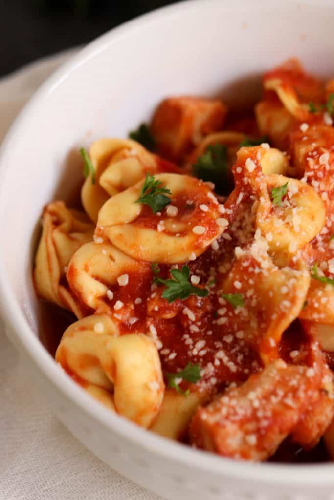 A serving of Slow Cooker Cheesy Chicken Tortellini in a white bowl.