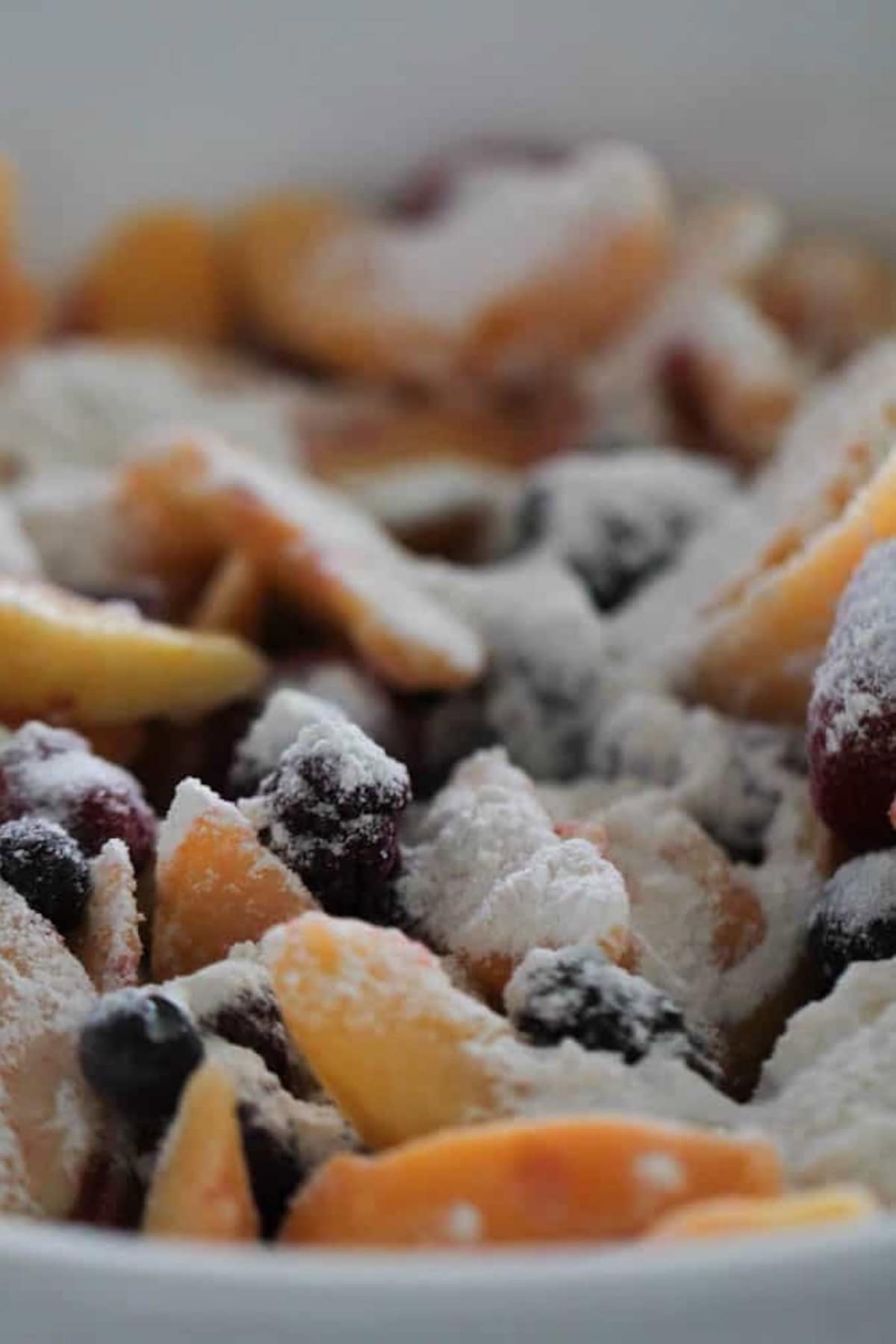 Flour and Sugar mixture tossed with frozen fruit in mixing bowl.