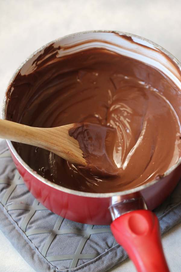 A saucepan with melted chocolate and a wooden spoon