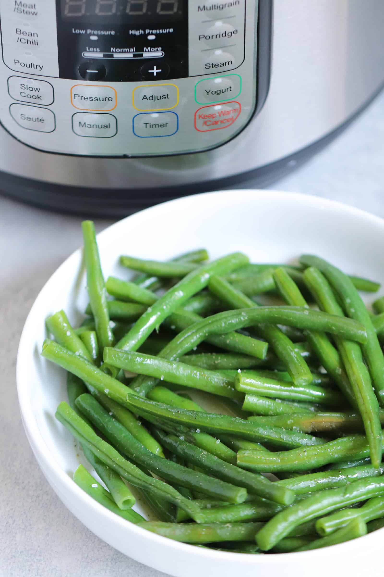 Cooked green beans in a bowl next to an Instant Pot