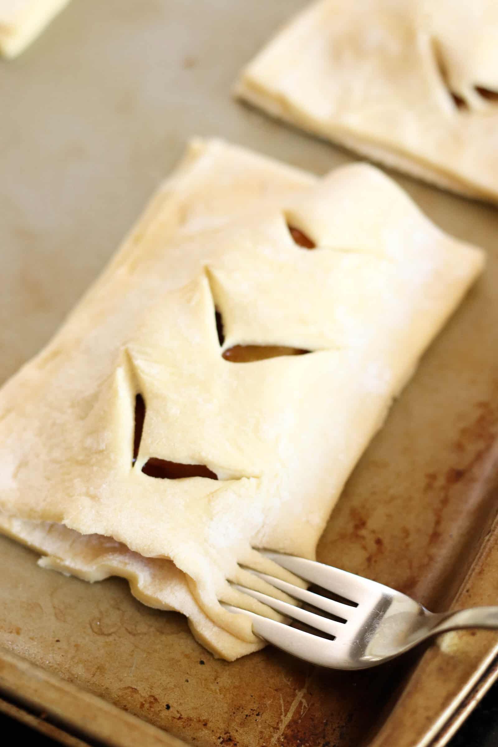 Fork pressing the crust together for Peach Hand Pies.