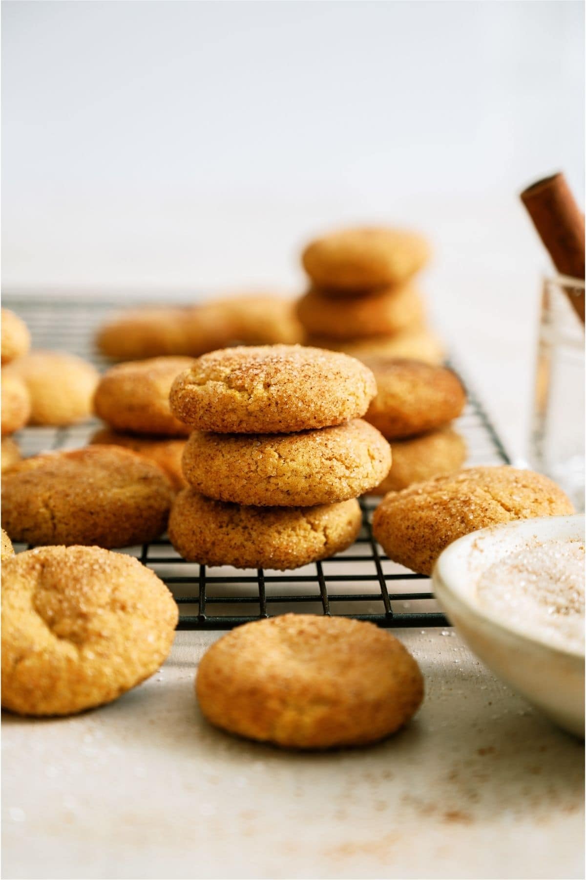 Side view of Pumpkin Snickerdoodle Cookies on a cooling rack with some stacked.