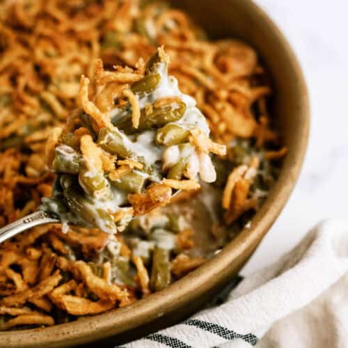 Classic Green Bean Casserole in casserole dish with a serving spoon lifting out a scoop.
