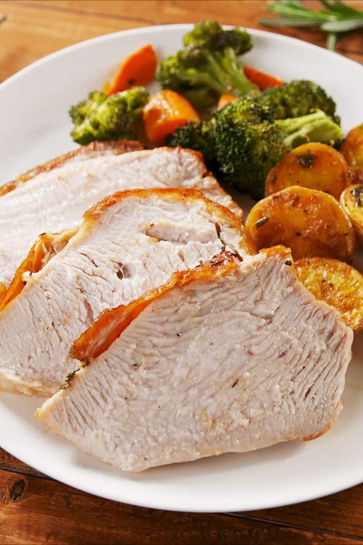 cooked and sliced turkey breast on a white plate with broccoli and sweet potatoes