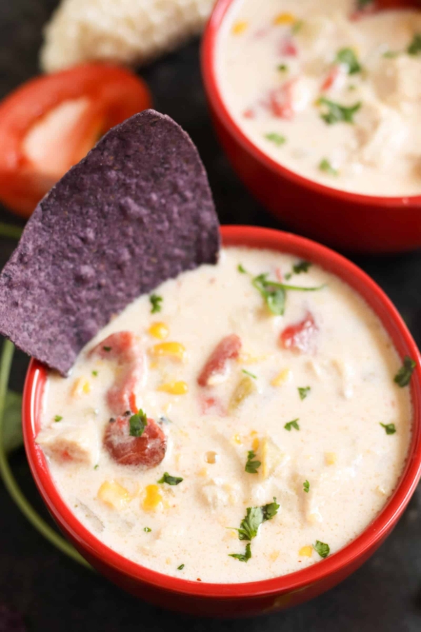 white cheddar corn chowder in a bowl with a purple tortilla chip