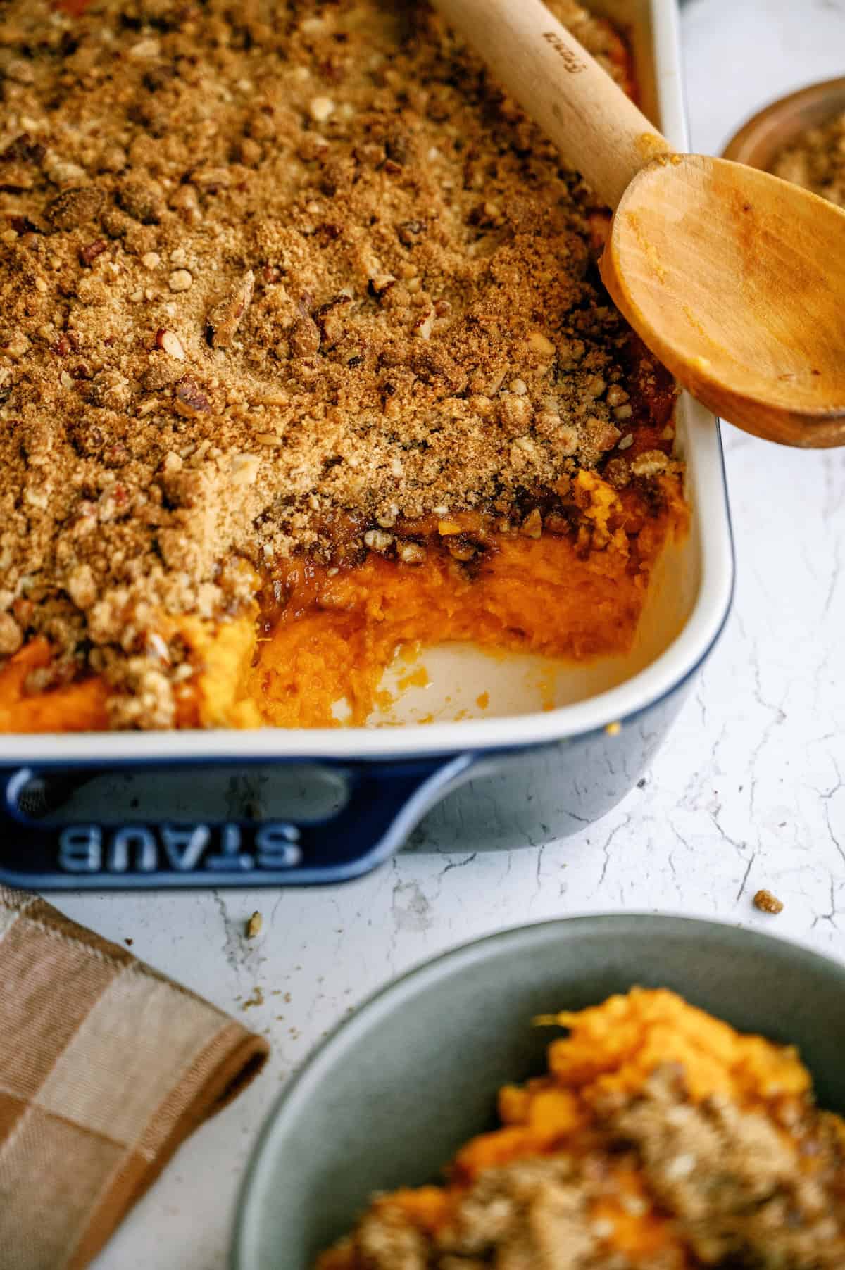 A glass baking dish filled with sweet potato casserole, topped with a brown sugar and pecan crumble.