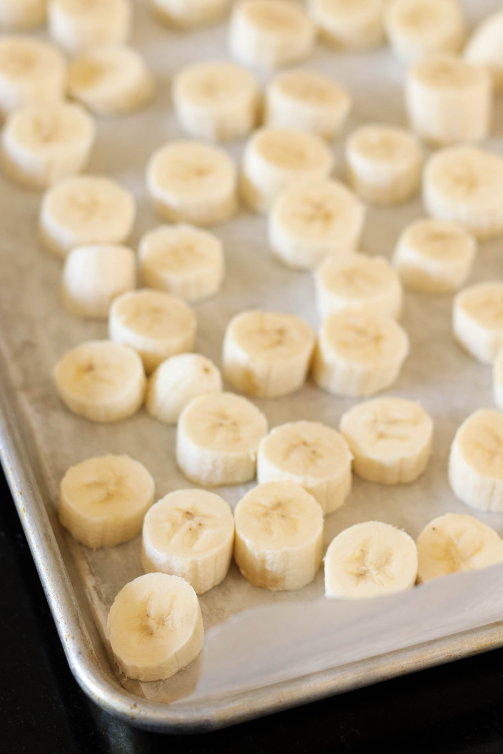 sliced frozen bananas on a sheet pan lined with wax paper