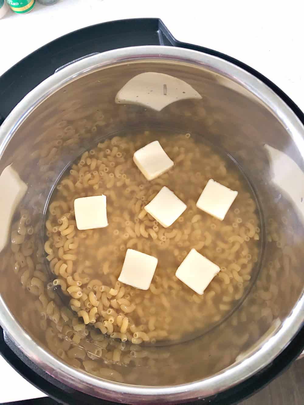 Pasta, butter, and water in bottom of instant pot. 