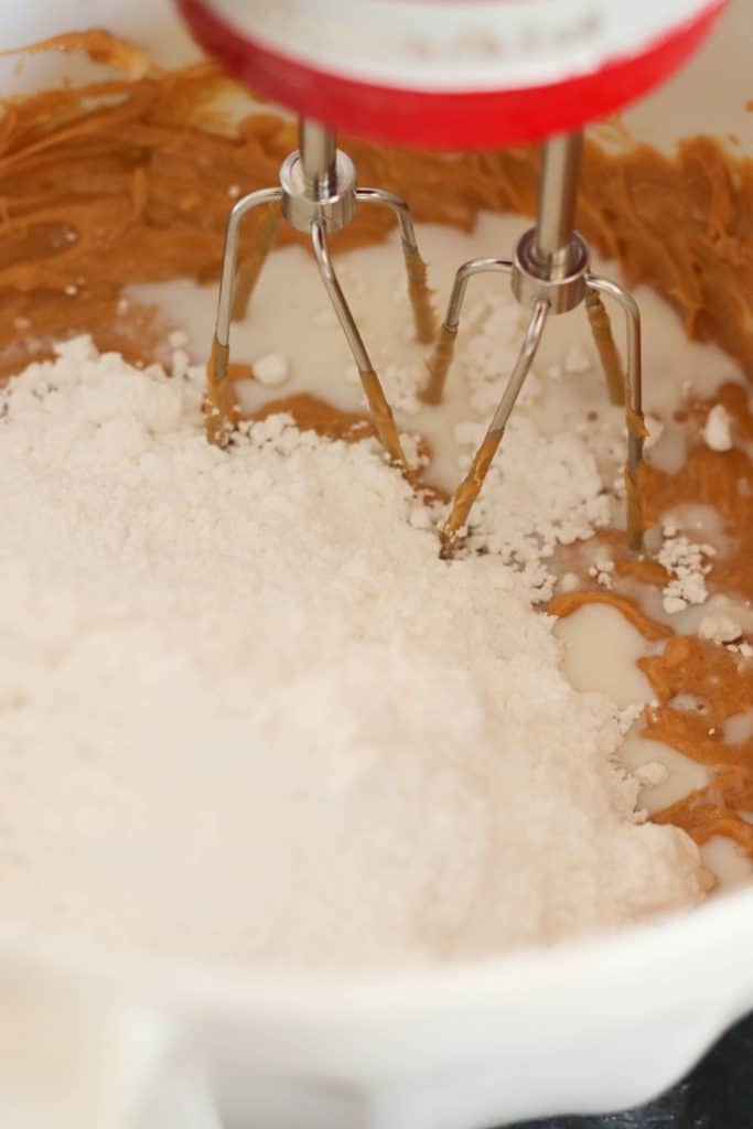 A mixer is mixing peanut butter and powdered sugar together.