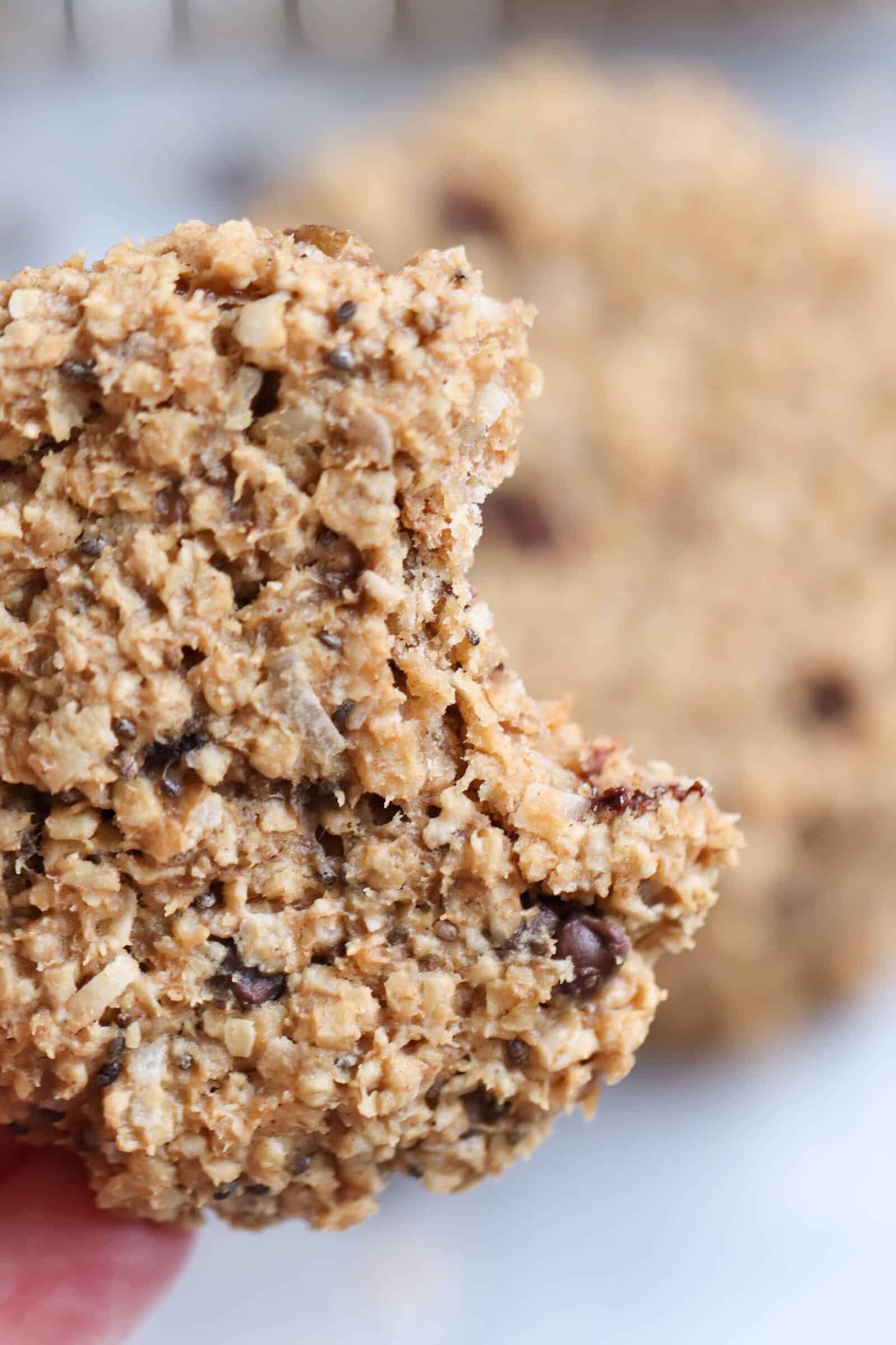 A breakfast cookie being held with a bite missing out of it.