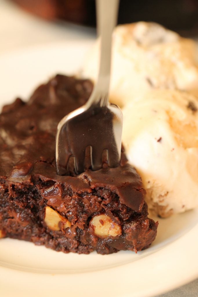 fudgy brownie piece with ice cream and being poked with a fork