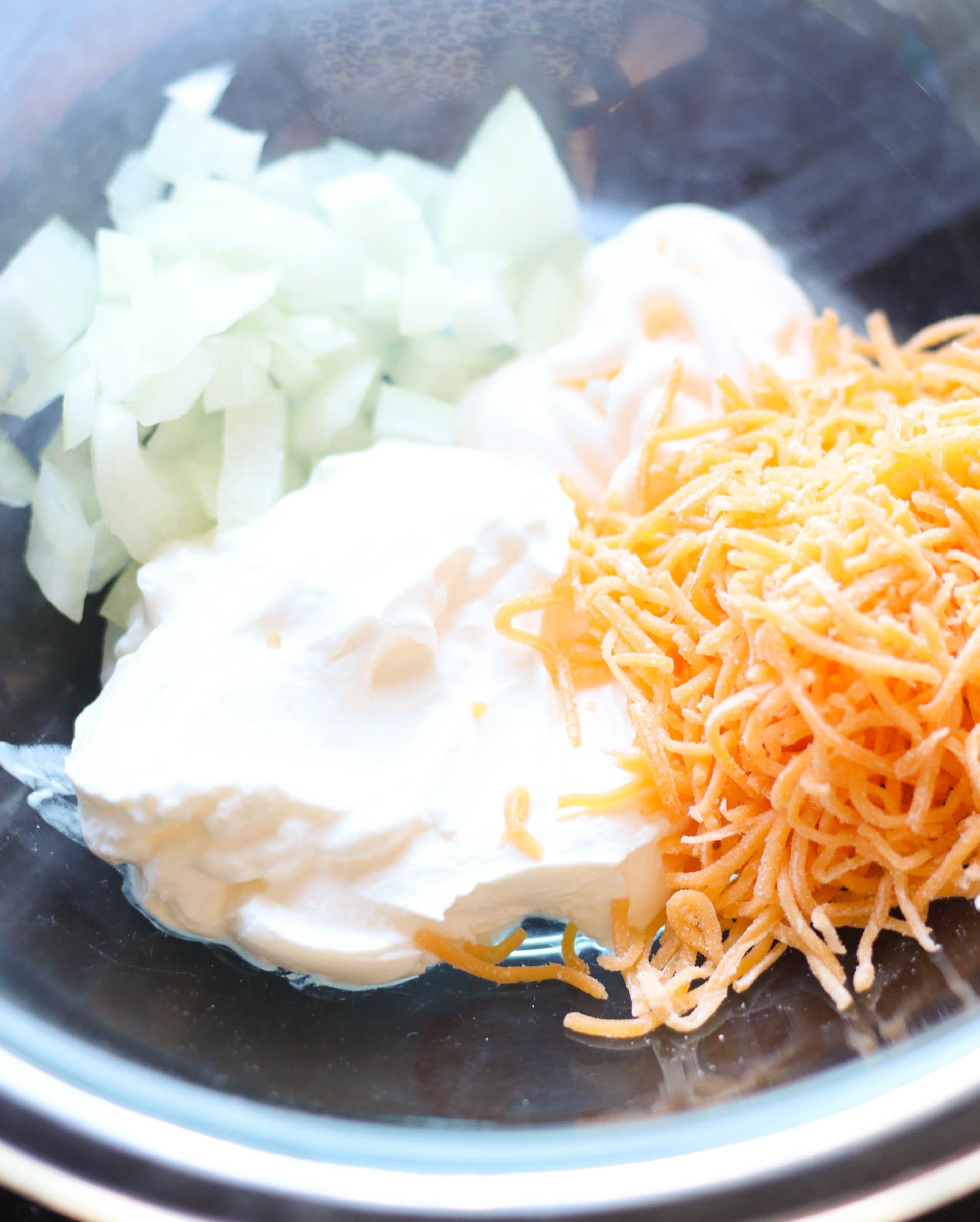 Mixing bowl with sour cream , cheese and onions