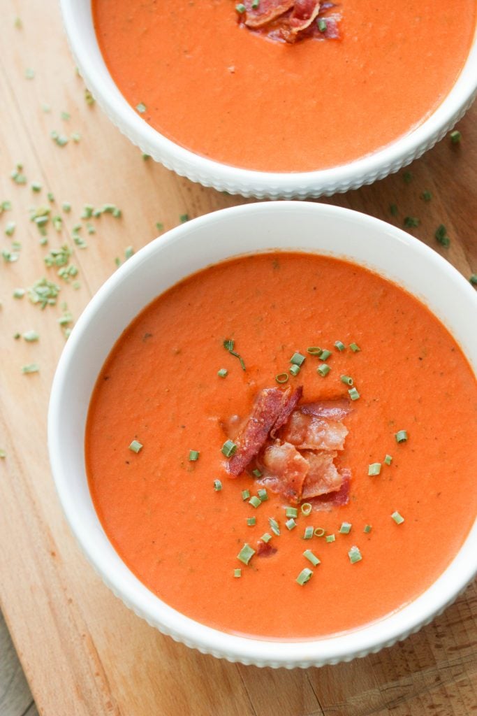 bacon tomato bisque soup in bowls topped with chives and bacon