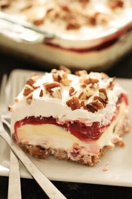 A slice of Layered Cherry Cheesecake Lush Dessert on a plate with a fork.