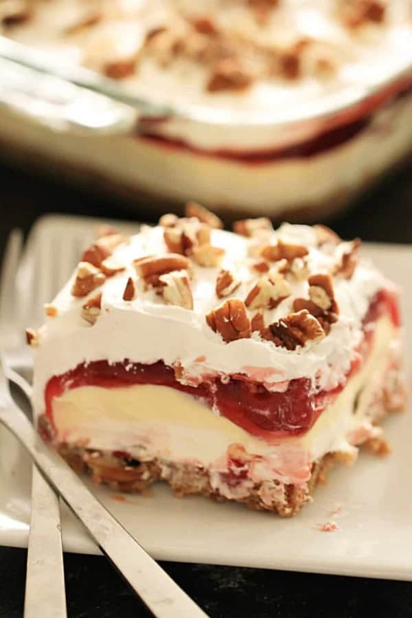 A slice of Layered Cherry Cheesecake Lush Dessert on a plate with a fork.