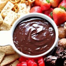 Assorted snacks including strawberries, brownies, pretzels, Rice Krispies treats, and gummy candies surround a bowl of chocolate dip.