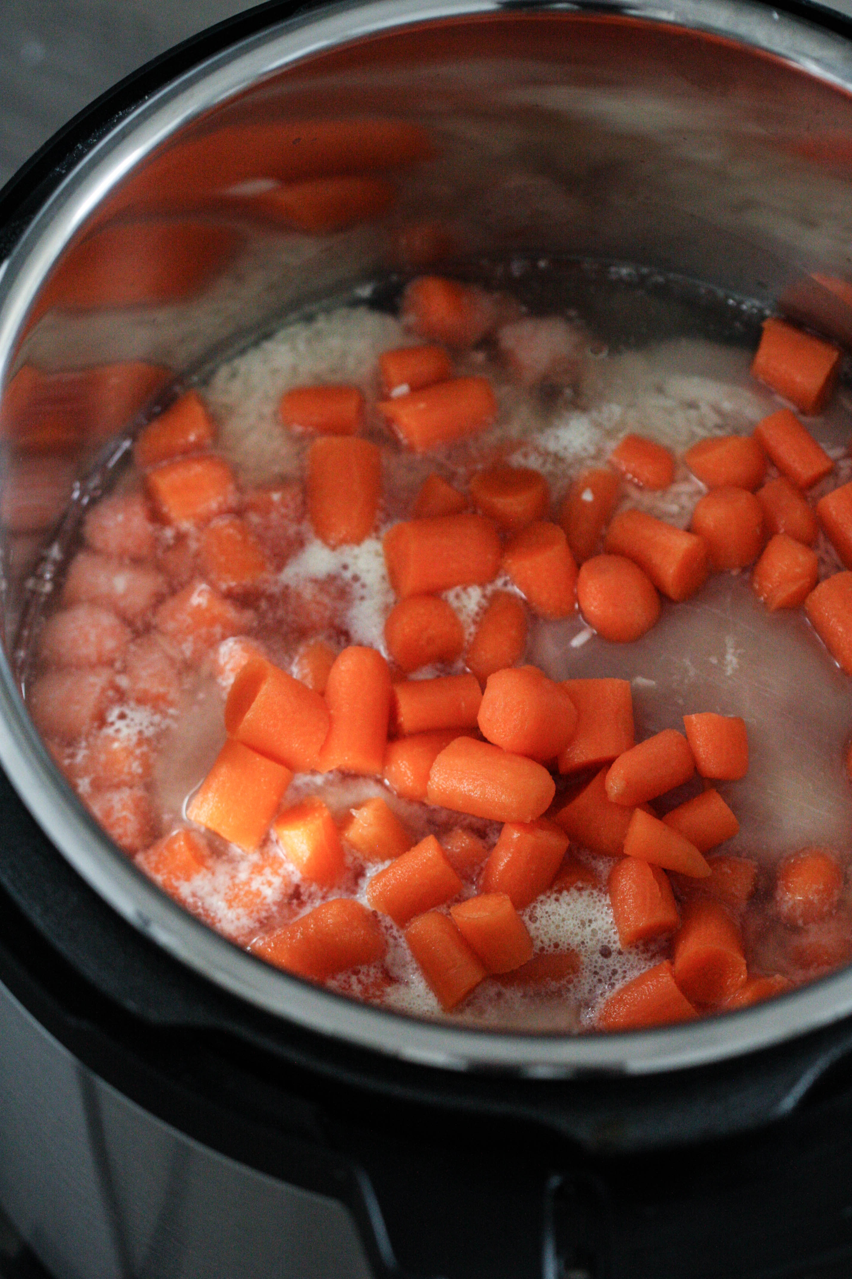 chicken and carrots in water in the inner portion of the instant pot