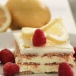 A slice of Lemon Ice Box Cake topped with thinly sliced lemon and raspberries.