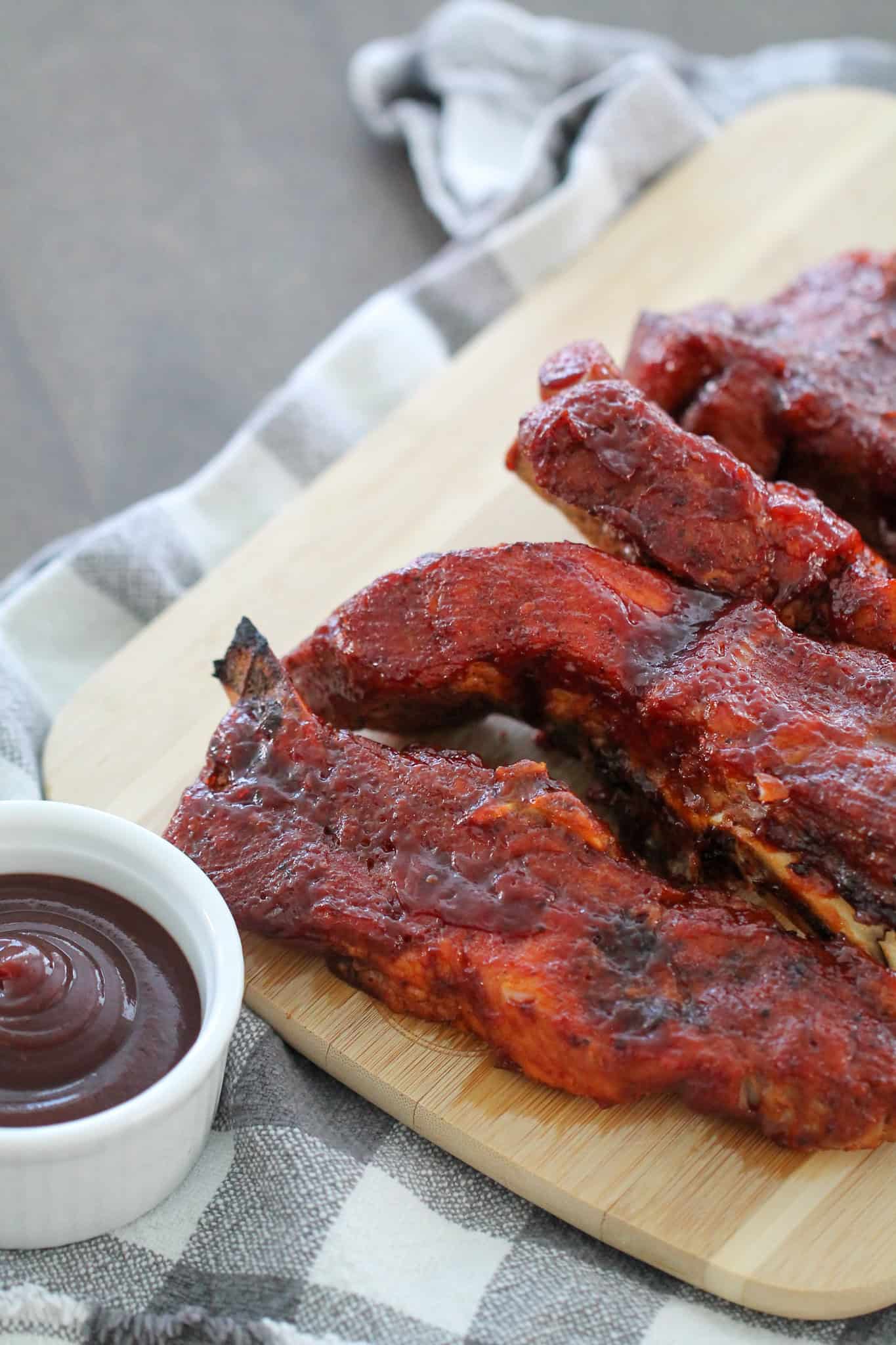 Instant Pot BBQ Country Ribs on a wooden cutting board with a side of BBQ Sauce