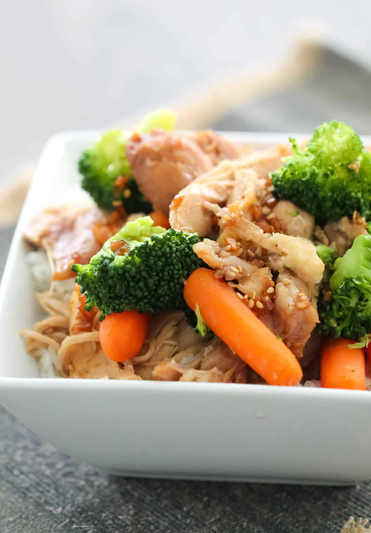 Slow Cooker Teriyaki Chicken in a white bowl with carrots and broccoli