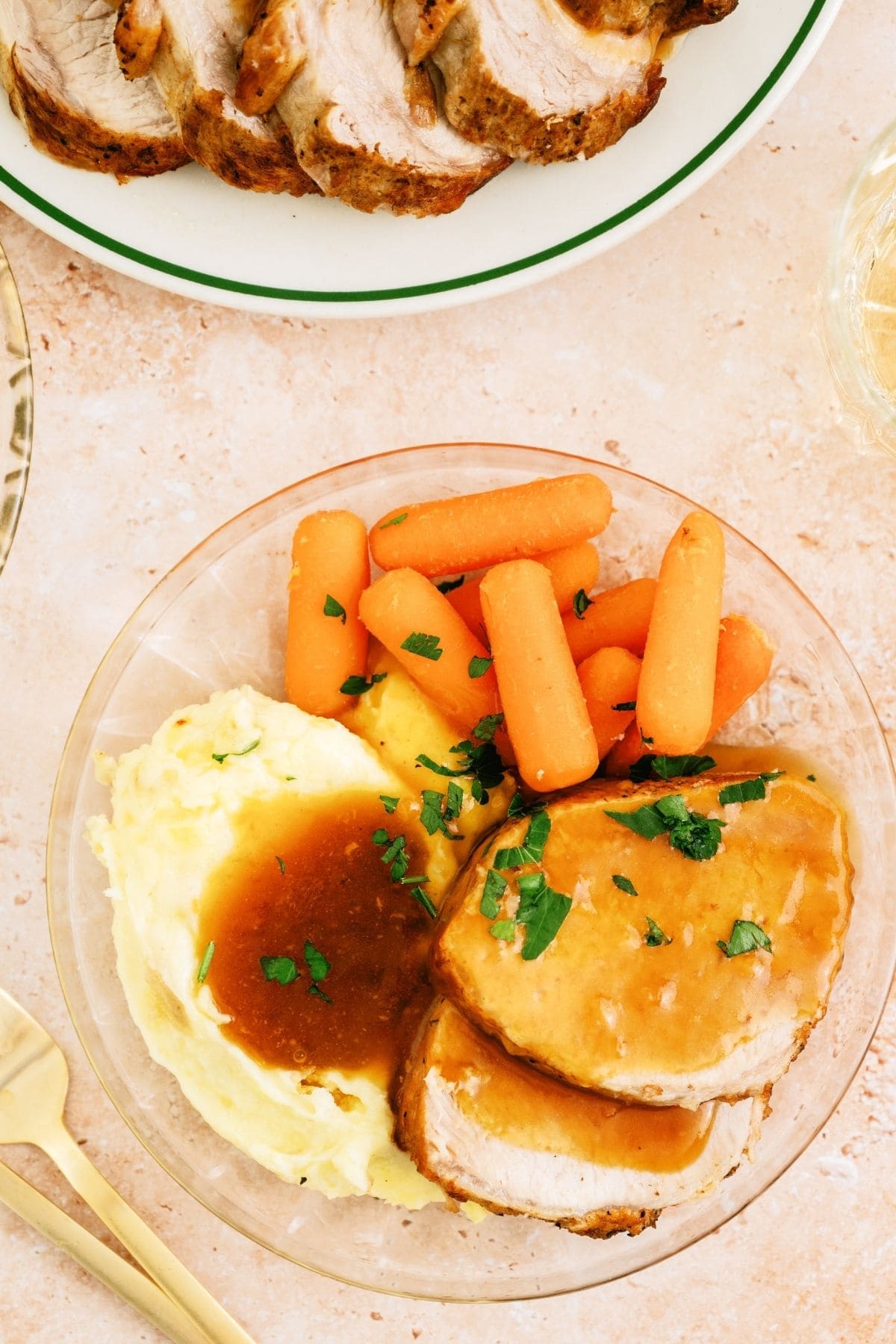 Slow Cooker Company Pork Roast slices on a plate with mashed potatoes and carrots.