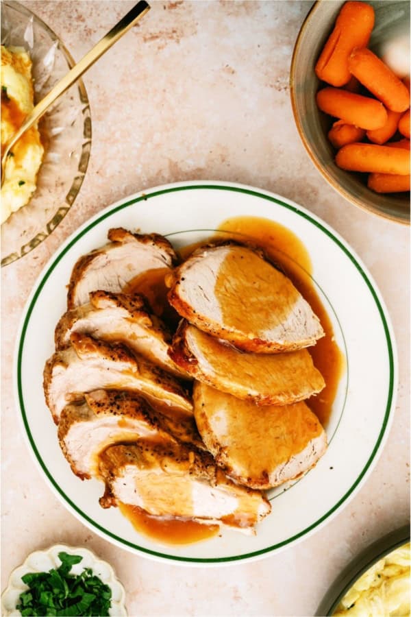 A plate of Slow Cooker Company Pork Roast sliced with gravy on top.