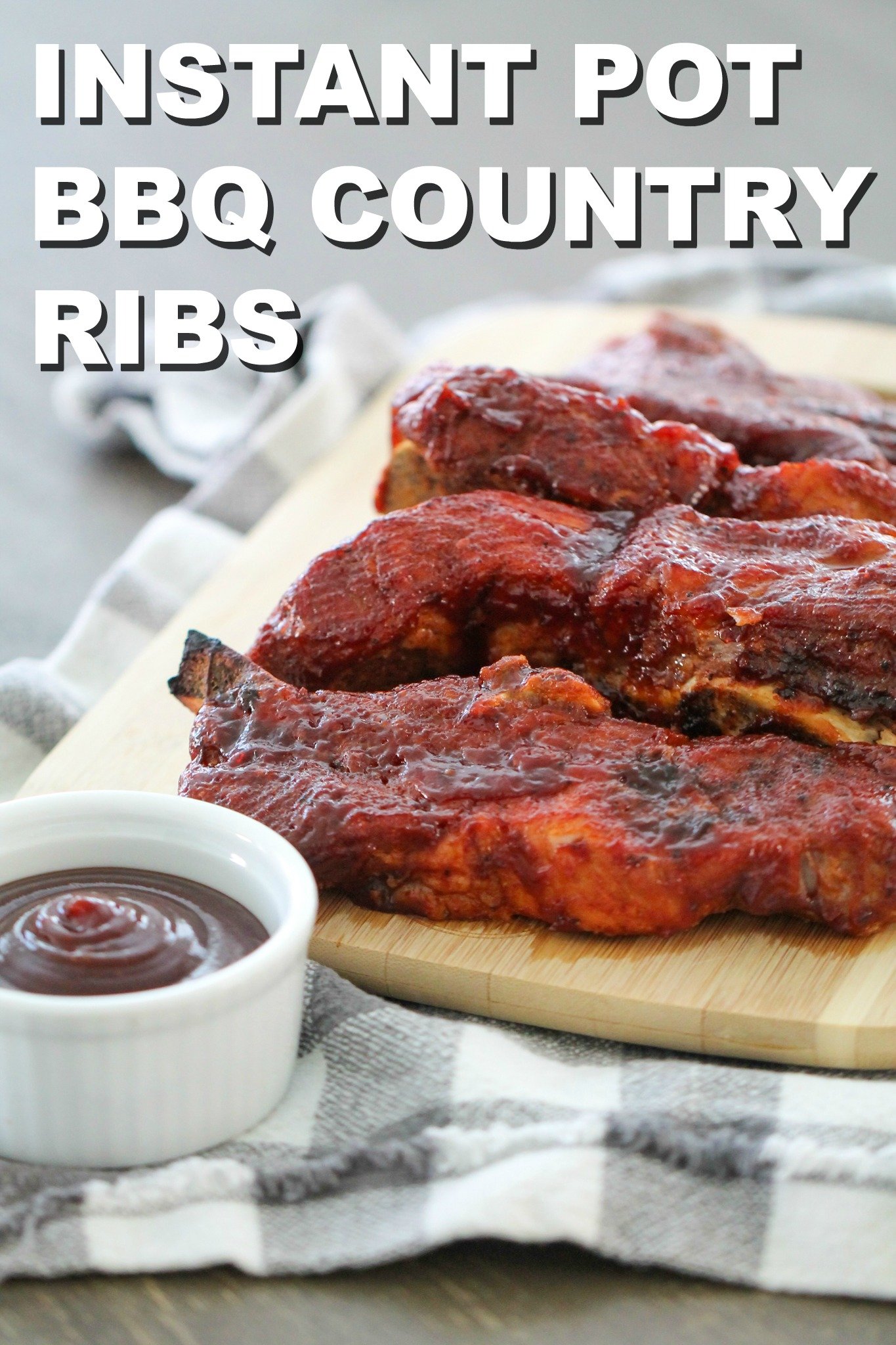 Instant Pot BBQ Country Ribs on a cutting board with a side of BBQ Sauce