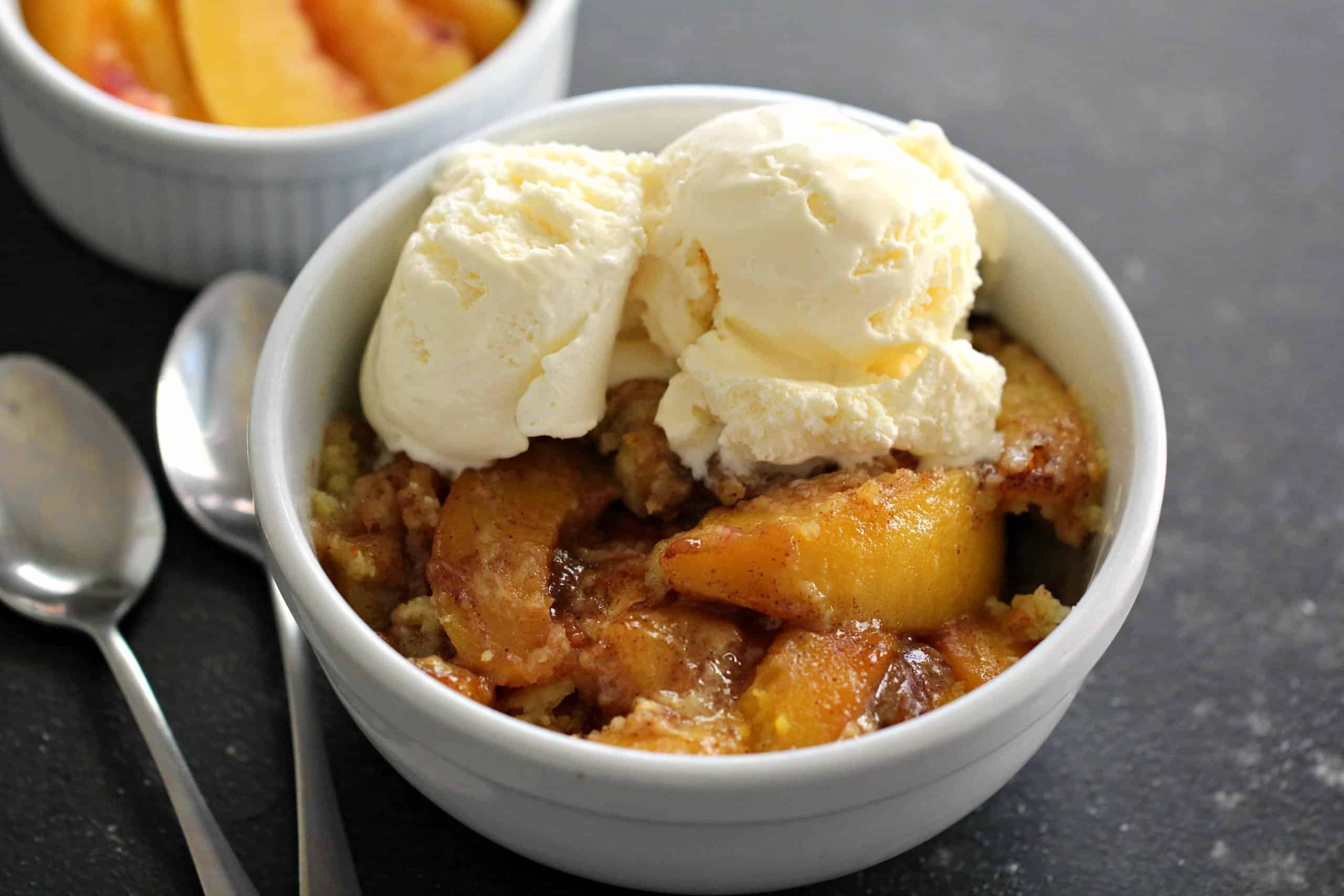 Easy Instant Pot Peach Cobbler in a white bowl topped with ice cream