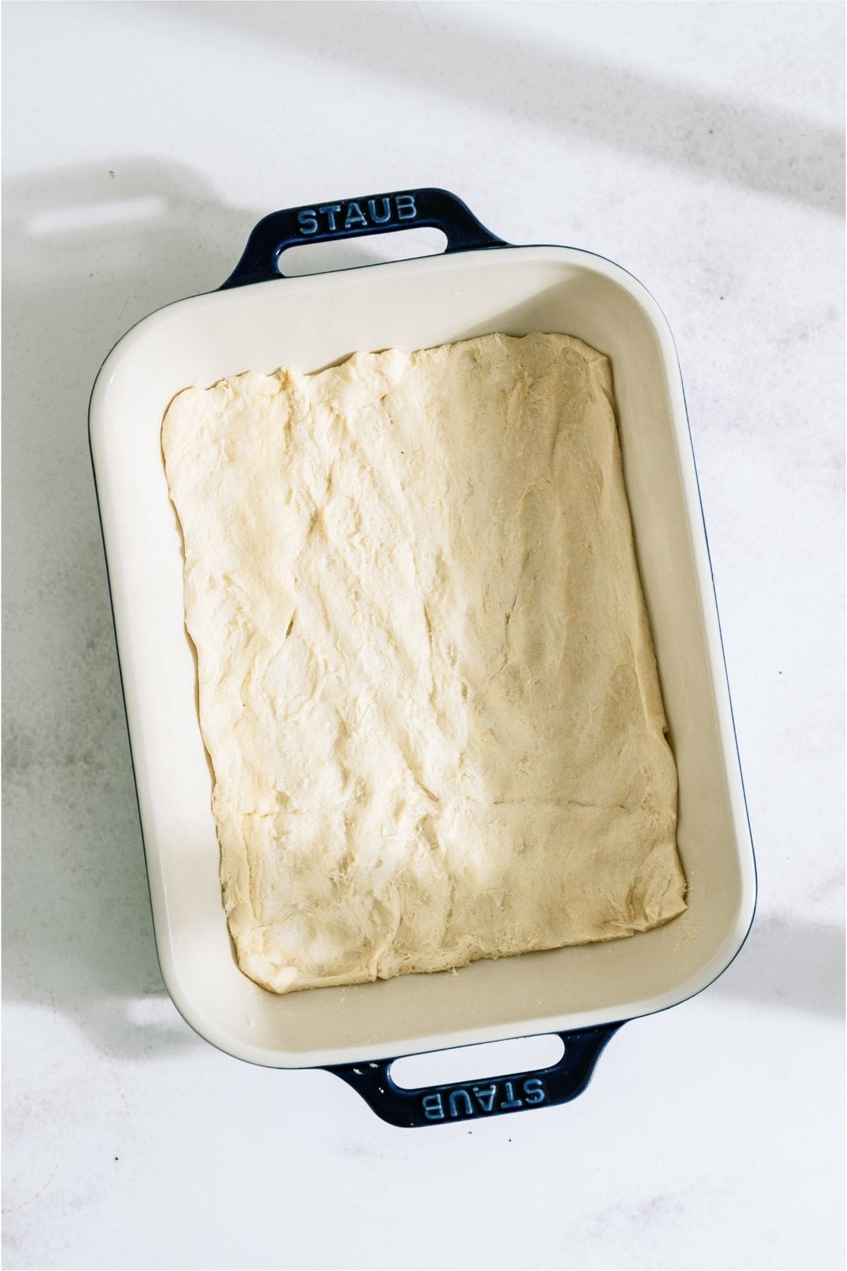 Flattened biscuit dough in a casserole dish.