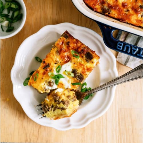 serving of Sausage Breakfast Casserole on a white plate with a fork.