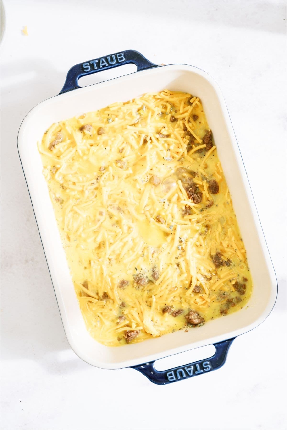 Egg mixture on top of cheese in casserole dish.