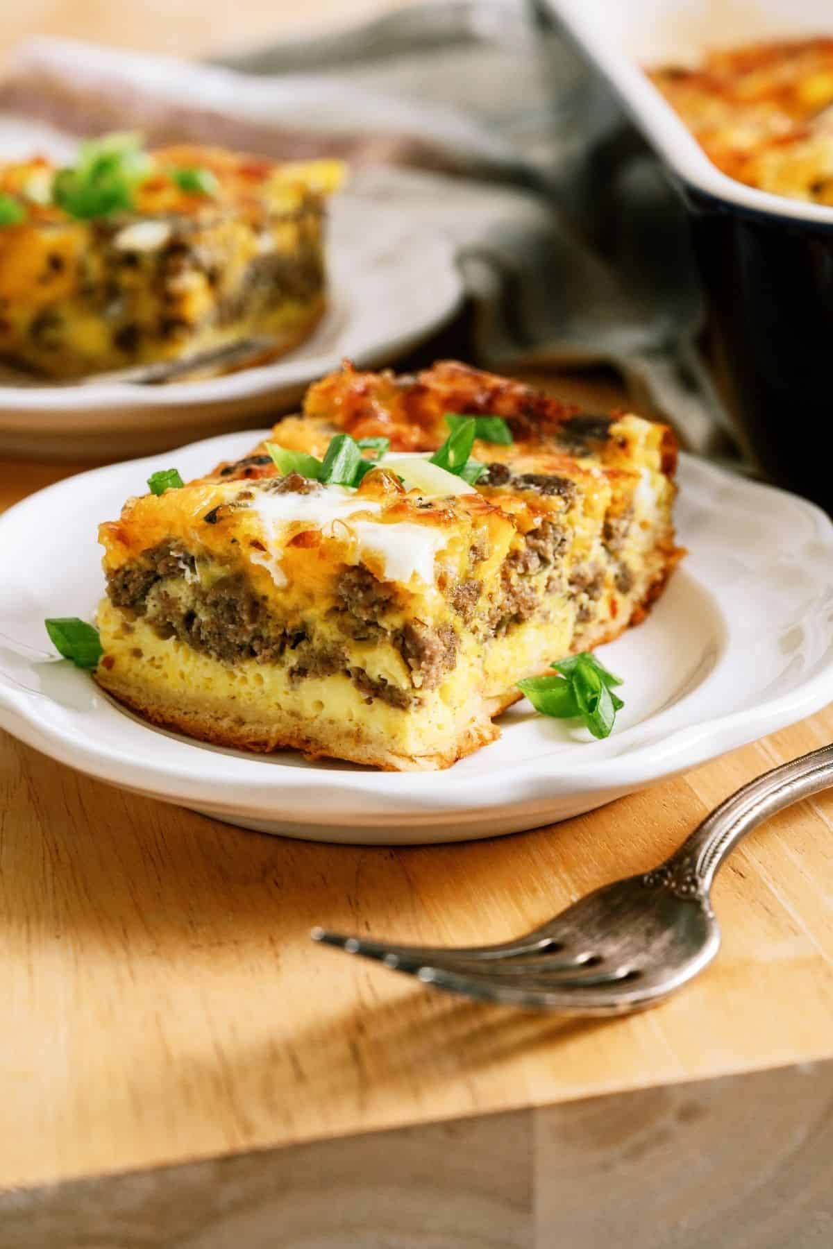 A slice of Sausage Breakfast Casserole on a plate with a fork.