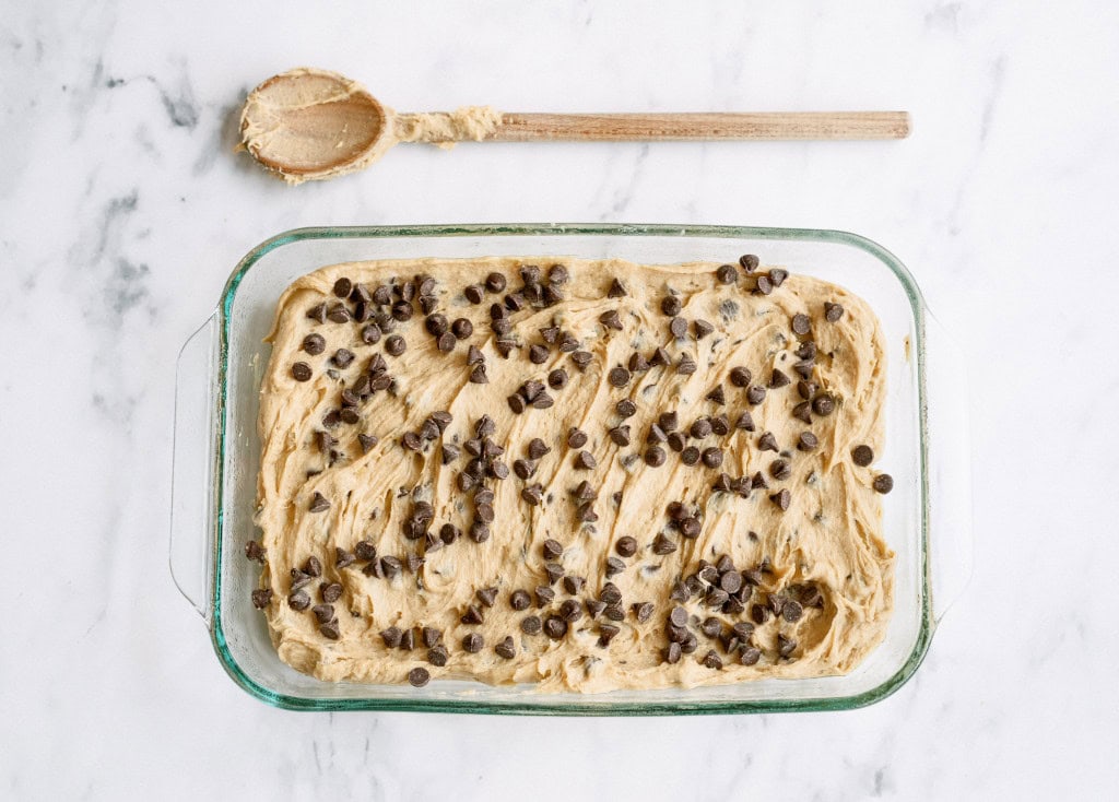 Chunky Monkey Brownies batter in a glass baking dish with chocolate chips sprinkled on top.