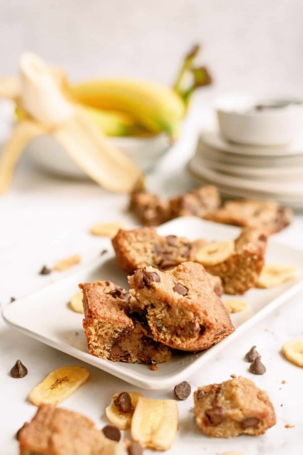 Chunky Monkey Brownies cut into squares on a white serving plate.
