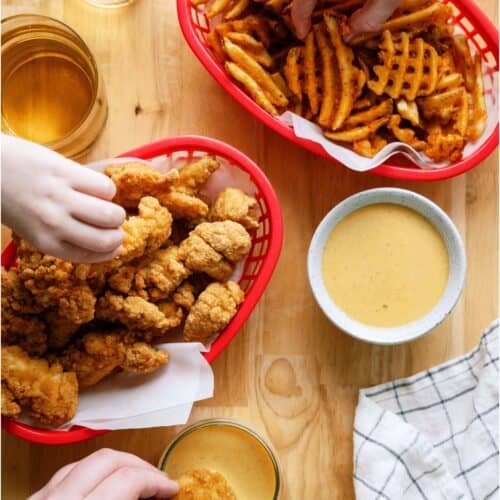 Several hands reaching in Chicken tender basket, french fries basket, and Copycat Chick-Fil-A Sauce bowl.