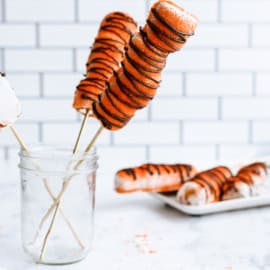 2 Copycat Disney Tigger Tails in a jar on skewers and 3 Copycat Disney Tigger Tails on a plate in the background.