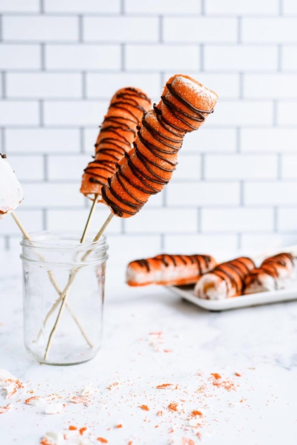 2 Copycat Disney Tigger Tails in a jar on skewers and 3 Copycat Disney Tigger Tails on a plate in the background.