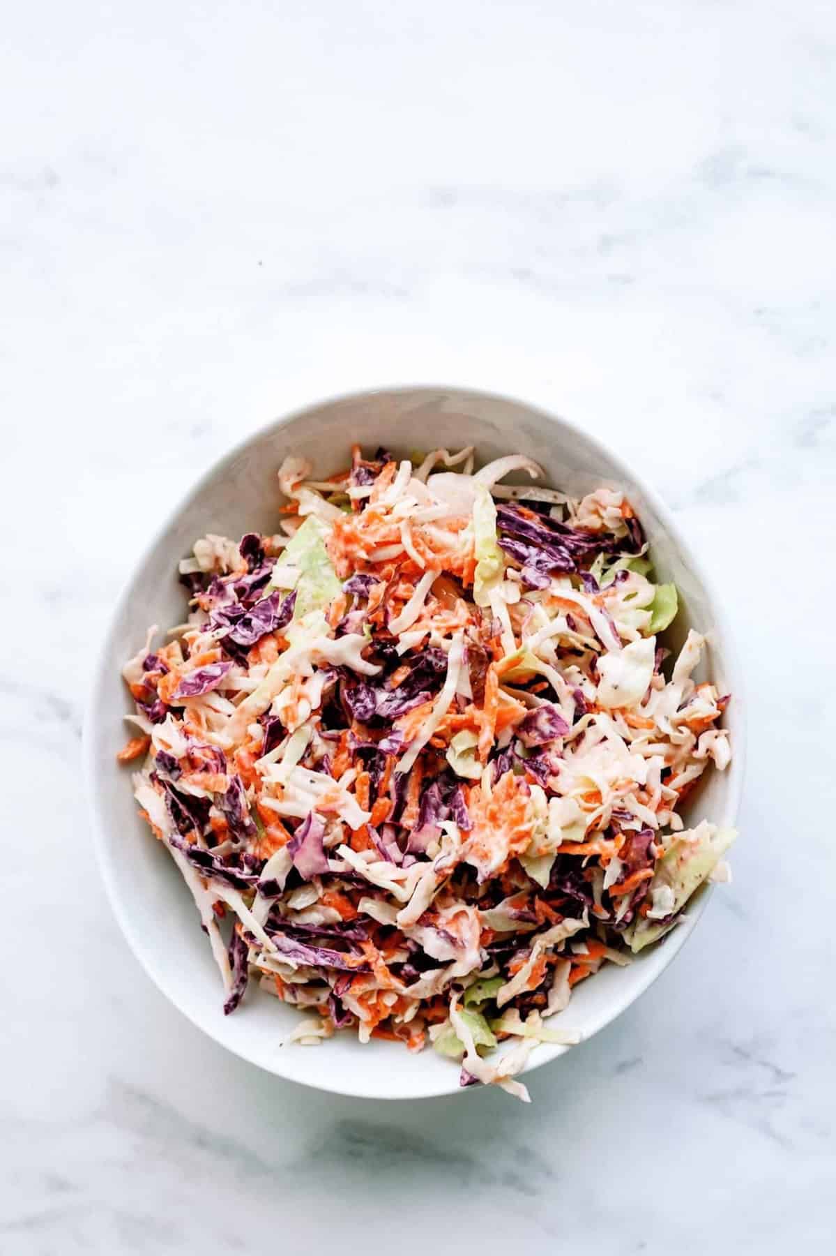 purple cabbage, shredded carrots, and green cabbage coleslaw in a bowl