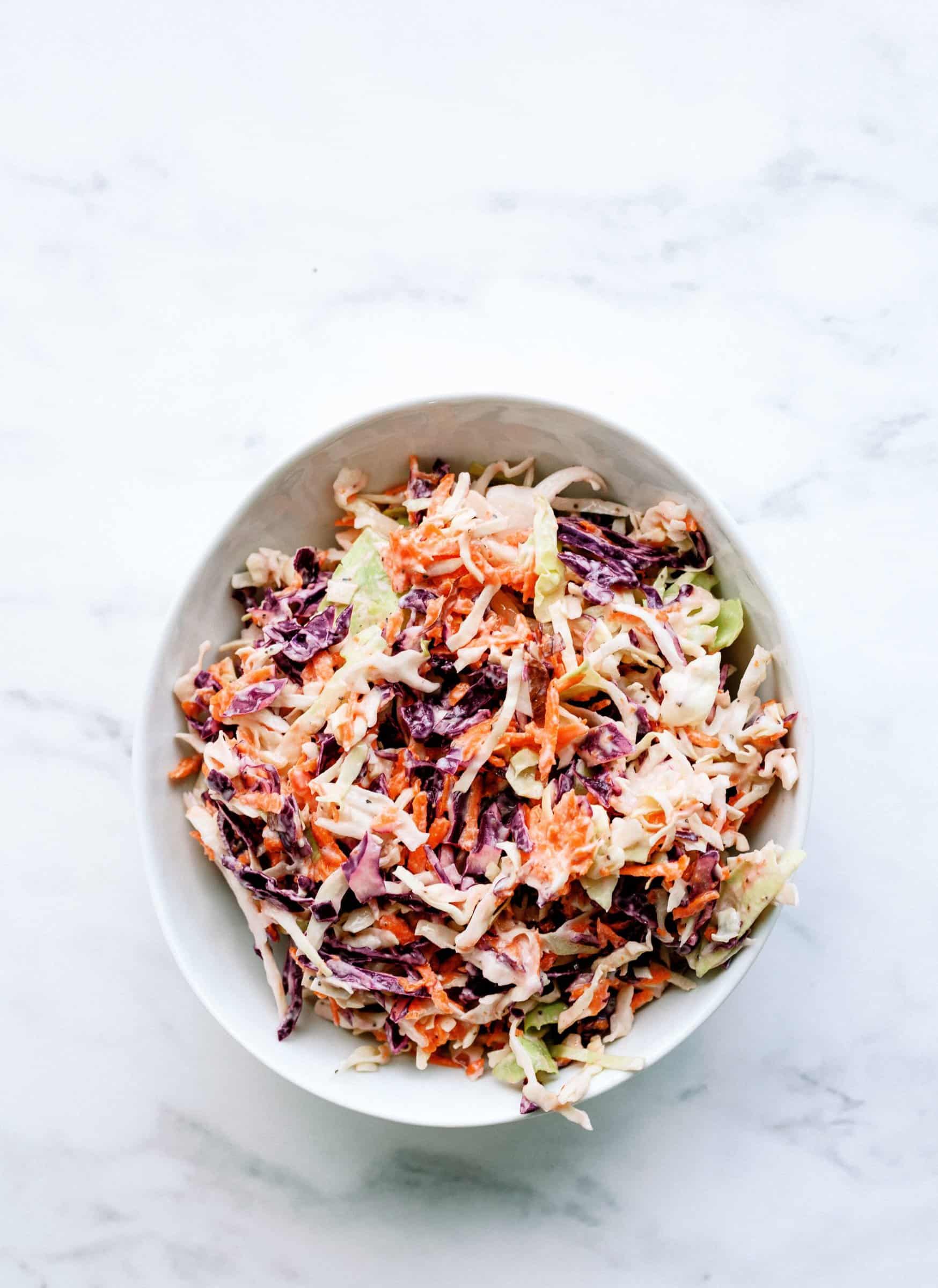 purple cabbage, shredded carrots, and green cabbage coleslaw in a bowl