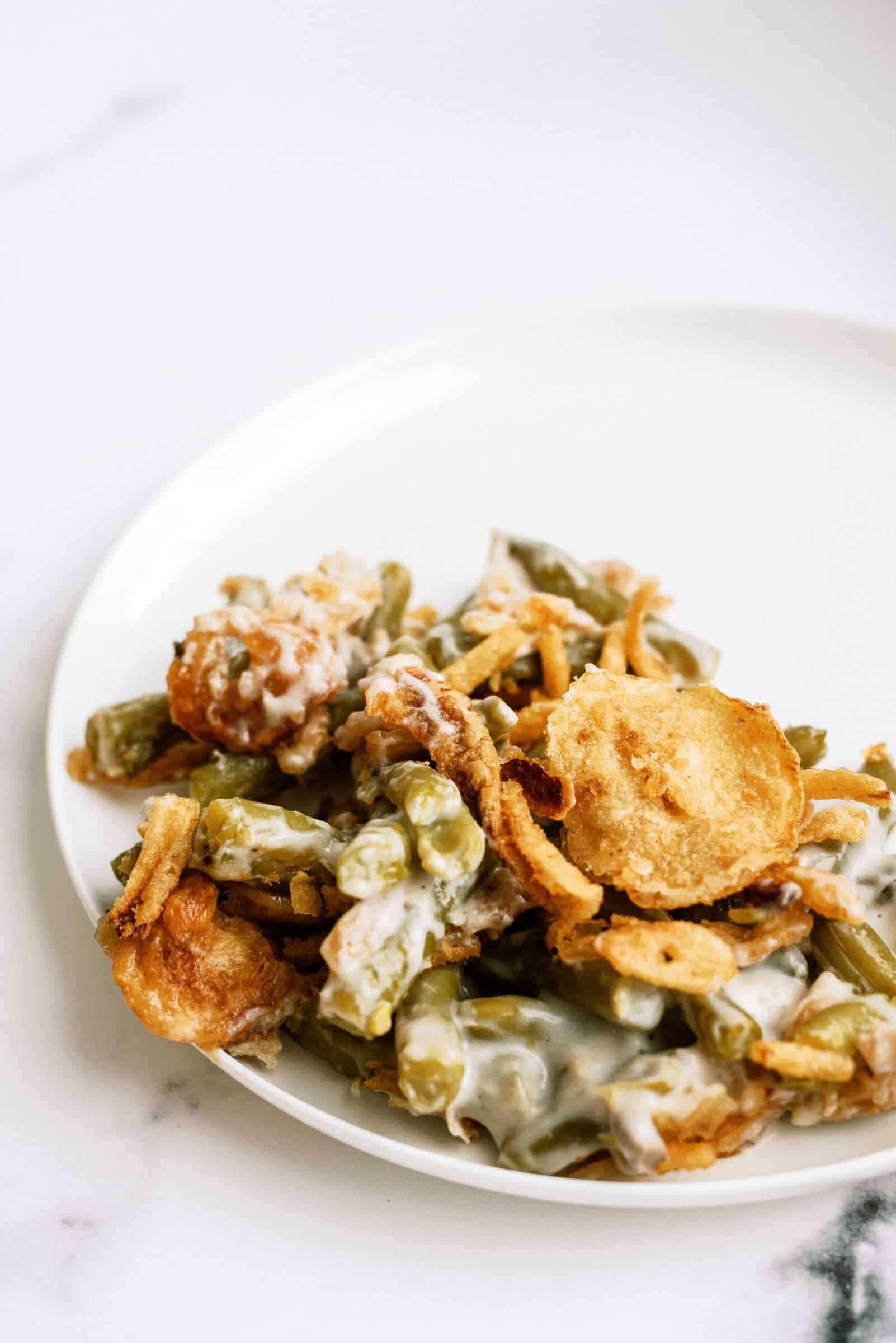 A serving of green bean casserole topped with crispy fried onions, served on a white plate.
